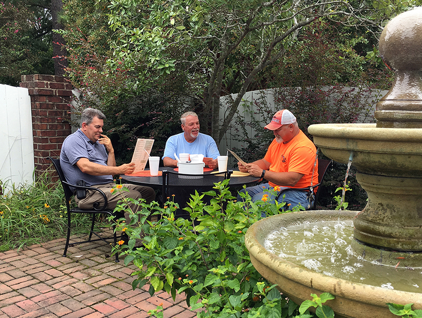 men sitting around outdoor dining table