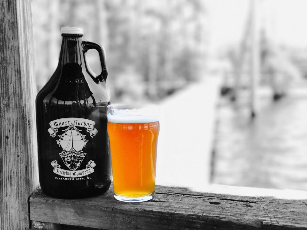 black and white ghost harbor brewery growler with pint of beer on the water